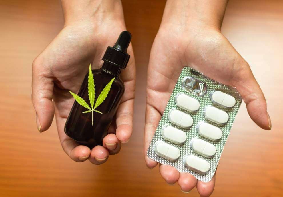 Hands holding CBD oil and prescription pills